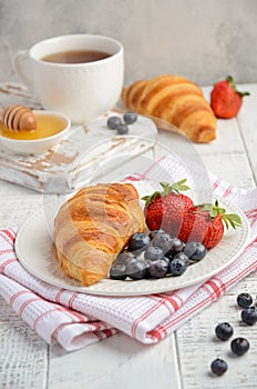 Fresh Croissants with fresh berries on rustic wooden background
