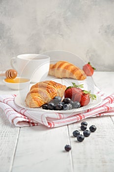 Fresh Croissants with fresh berries on rustic wooden background