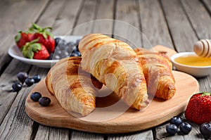 Fresh Croissants with fresh berries on rustic wooden background