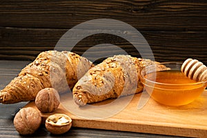 Fresh croissants with honey jar and nuts