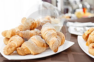 Fresh croissants on white plate. French traditional pastry. Breakfast in hotel smorgasbord.