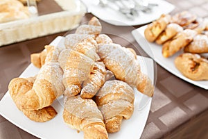 Fresh croissants on white plate. French traditional pastry. Breakfast in hotel smorgasbord.