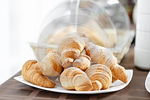 Fresh croissants on white plate. French traditional pastry. Breakfast in hotel smorgasbord.