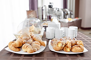 Fresh croissants on white plate. French traditional pastry. Breakfast in hotel smorgasbord.