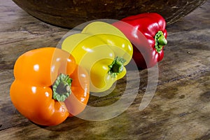 Fresh crop of sweet pepper, red, orange, yellow on a wooden table