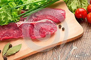 Fresh, crude, raw stakes from meat veal on a wooden chopping board with setion