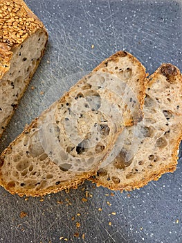 fresh crusty bread, artisan wheat bread, crispy and browned crust, sliced bread slices, grains and seeds