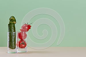 Fresh cucumber and ripe tomato in glass. Fresh juice. Healthy lifestyle concept. Copy space. Isolated on green backdrop