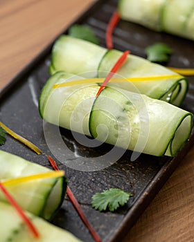 Fresh Cucumber rolls, vegetarian appetizer. Elegant vegetable dish on black plate. Healthy food. Spring vitamin snack