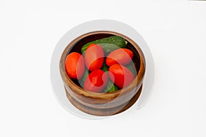 Fresh cucumbers and tomatoes in a wooden bowl on the white wooden table