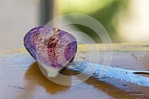 Fresh, cut fig with a knife on a wooden table.
