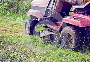 Fresh cut grass flying from riding lawnmower person cutting long