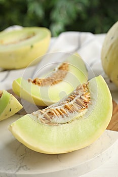 Fresh cut honeydew melon on white wooden table, closeup