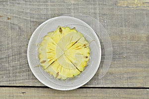 Fresh cut pineapple in white plate on wooden backgroundn