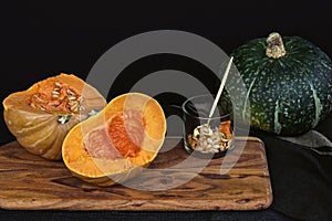 Fresh cut pumpkin with seeds on wooden board with black background