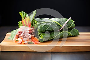 fresh cut vegetables wrapped in collard greens on a board
