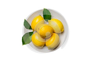 Fresh cutted lemon and whole lemons over round plate isolated on white background. Food and drink ingredients preparing