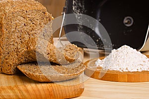 Fresh cutted loaf of rye bread and some flour on photo