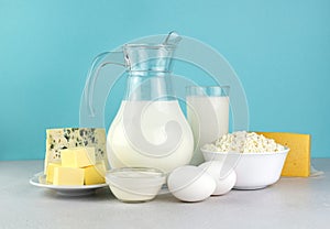 Fresh dairy products, milk, cottage cheese, eggs, cheese, sour cream and butter on a blue background.