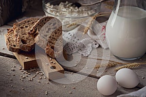 Fresh dairy products. Milk, cottage cheese, sour cream, multigrain homemade bread, fresh eggs and wheat on wooden background.