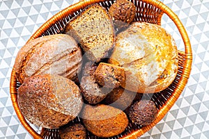 Fresh dark, grain and white bread in a basket on a tablecloth. Selective focus