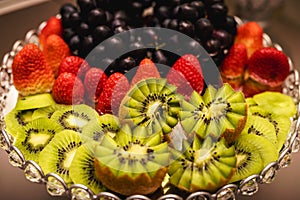 Fresh decorated kiwi with berries, strawberry and grapes in the background, spot focus. decorated fruits