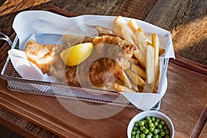 Fresh delicios fish and chips with lemon on the wooden table