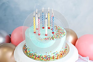 Fresh delicious birthday cake with candles near balloons