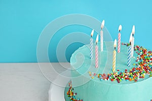 Fresh delicious birthday cake with candles on table against color background.