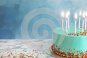 Fresh delicious birthday cake with candles on table against color background.