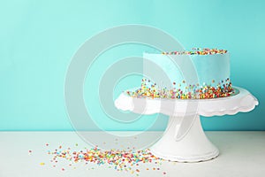 Fresh delicious birthday cake on stand against color background.