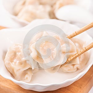 Fresh, delicious boiled pork, shrimp gyoza dumplings on white background with soy sauce and chopsticks, close up, lifestyle.