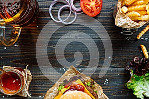 Fresh delicious burgers with french fries, sauce and beer on the wooden table top view