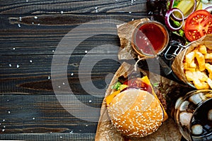 Fresh delicious burgers with french fries, sauce and drink on the wooden table top view, with copy space