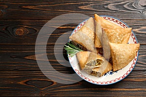 Fresh delicious crispy samosas served on wooden table, top view. Space for text