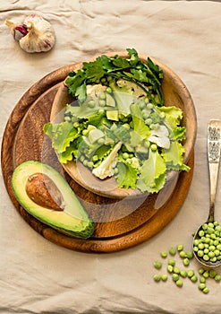 Fresh delicious green salad with avocado in a wooden plate and gluten free toast. Top view. Healthy lunch dish and Diet detox food