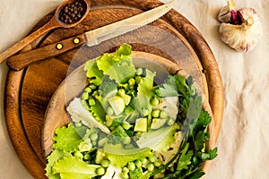 Fresh delicious green salad with avocado in a wooden plate and gluten free toast. Top view. Healthy lunch dish and Diet detox food