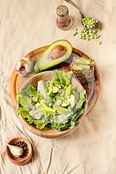 Fresh delicious green salad with avocado in a wooden plate and gluten free toast. Top view. Healthy lunch dish and Diet detox food