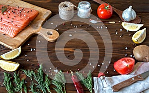 Fresh delicious salmon fillet with aromatic herbs, spices, garlic, lemon on dark background. Top view. Closeup.