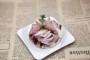 Fresh delicious Spanish tapas with hamon on the background of newspapers. Great background for restaurant, cafe