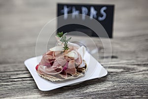 Fresh delicious Spanish tapas with hamon with fresh herbs and strawberries with poster TAPAS on the wooden background . Great bac