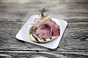 Fresh delicious Spanish tapas with hamon on the wooden background . Great background for restaurant, cafe