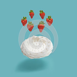 Fresh delicious strawberries in the circle floating in the air above levitated sweet meringue Pavlova cake. Blue sky background