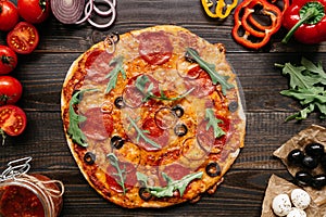 Fresh delisious pizza with pizza ingredients on the wooden table, top view