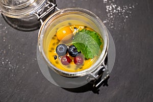 Fresh dessert in a glass jar with passion fruit and berries
