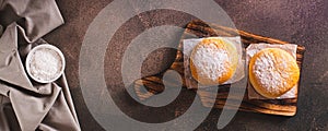Fresh donuts with powdered sugar and sweet filling on a plate on the table top view web banner