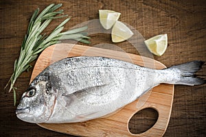 Fresh dorada with ingredients on the wooden board