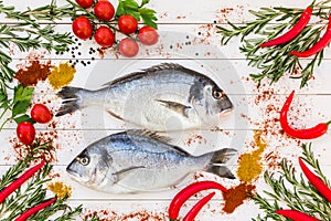 Fresh dorado fish, rosemary, cherry tomatoes, chilly pepper on white wooden table. Top view