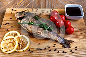 Fresh dorado grill with lemon and cherry tomatoes on a wooden tray. For restaurant menu or recipe