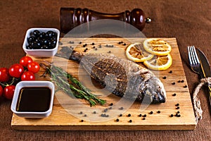 Fresh dorado grill with lemon and cherry tomatoes on a wooden tray. For restaurant menu or recipe